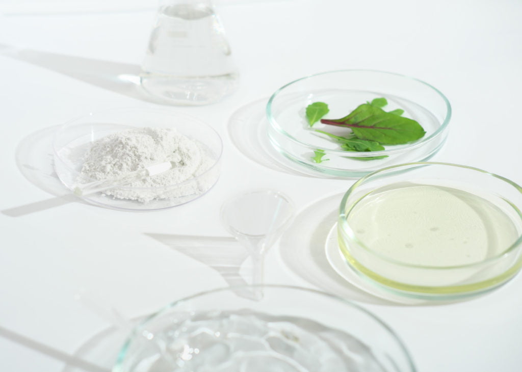 cosmetic skincare herbal medicine with green leaves natural sunlight chemical glassware petri dishes vials natural skincare